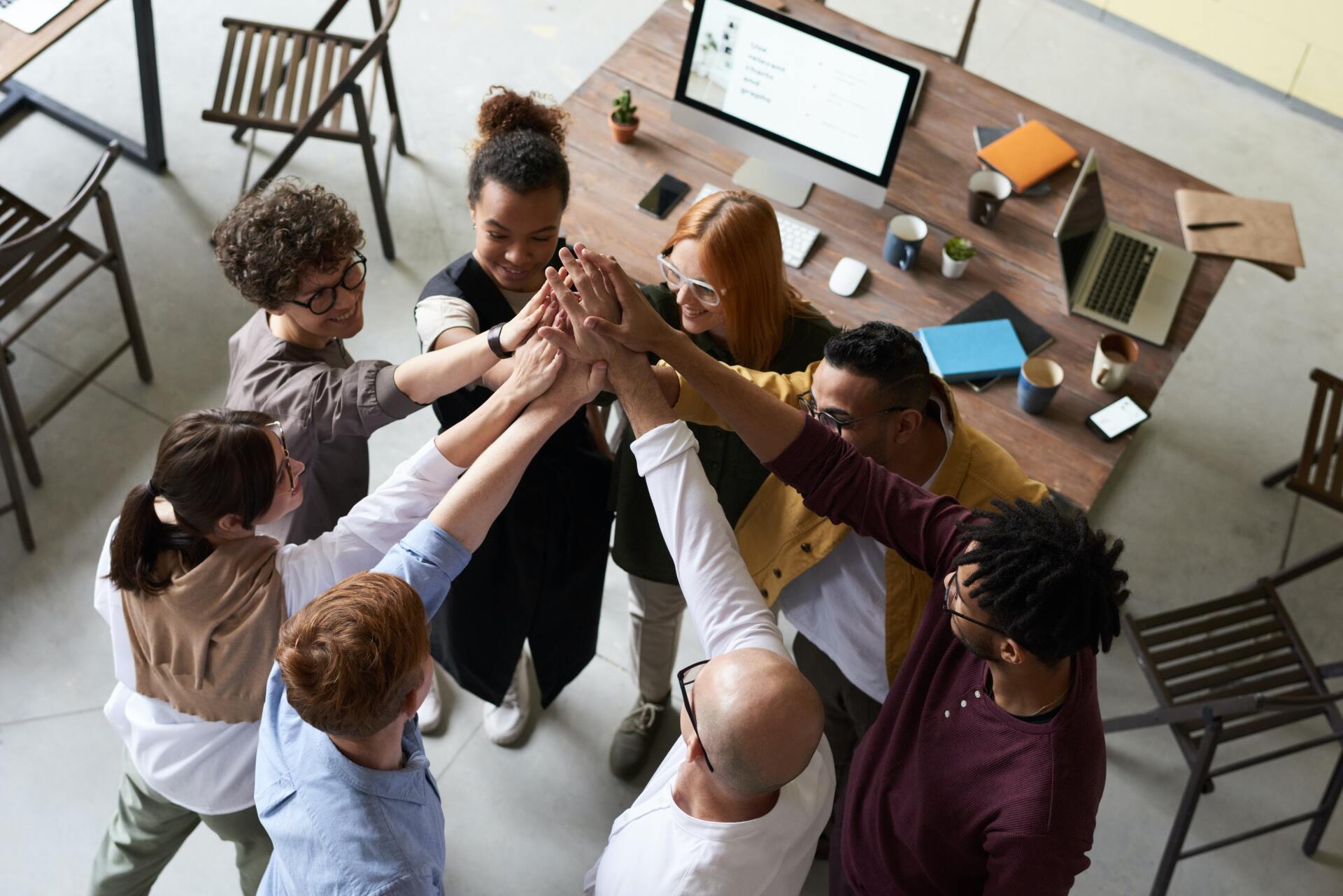 A group of people are giving each other a high five in an office.