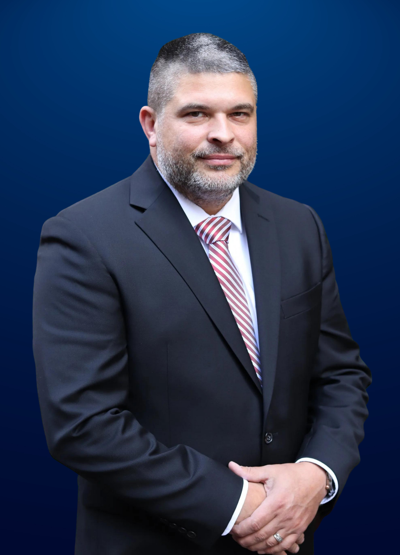 A man in a suit and tie is standing in front of a blue background.