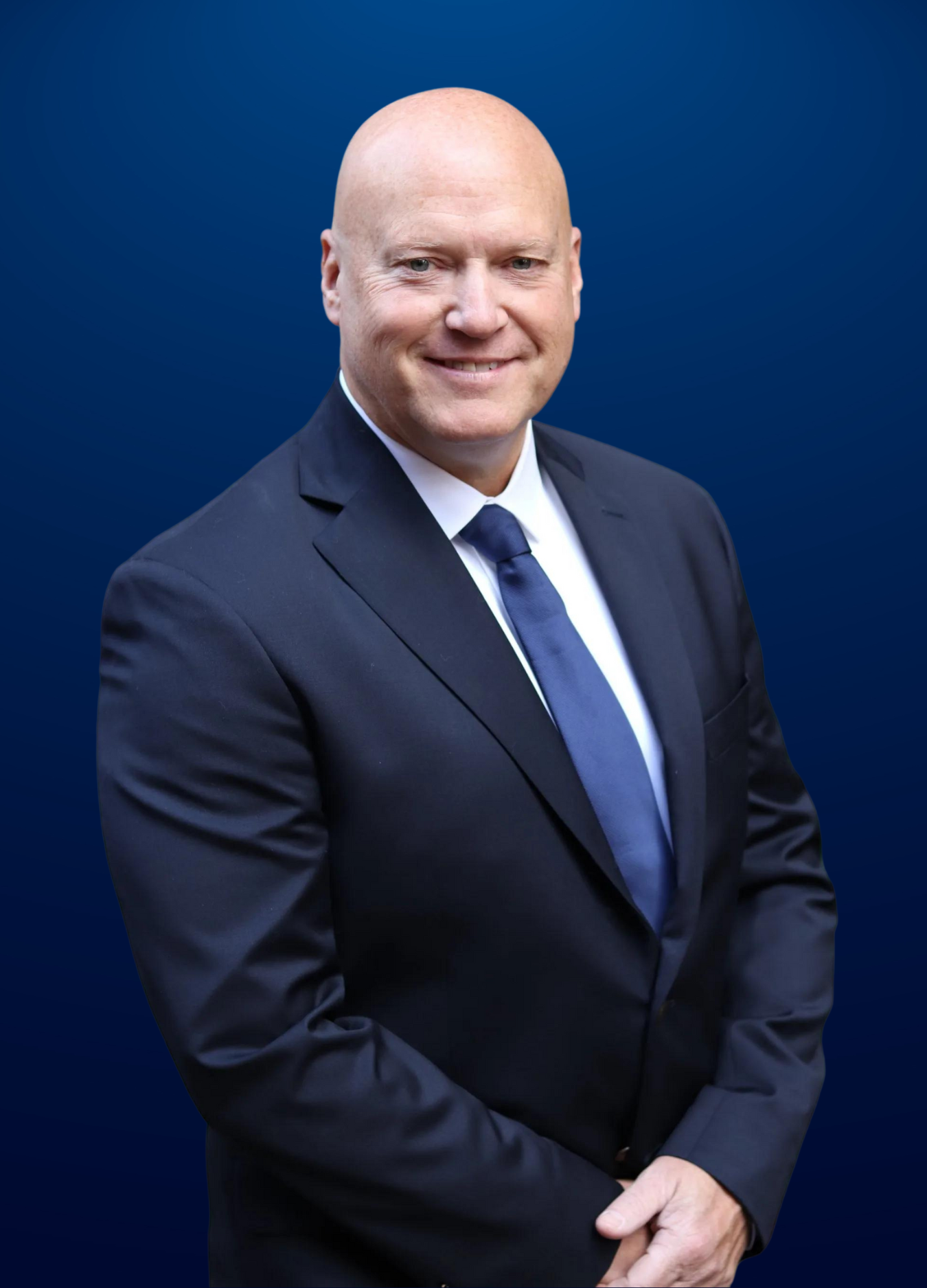 A man in a suit and tie is standing in front of a blue background.