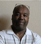 A man wearing glasses and a white shirt is smiling for the camera.