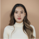 A woman with long hair is wearing a white turtleneck and earrings.