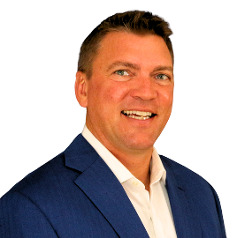 A man in a blue suit and white shirt smiles for the camera