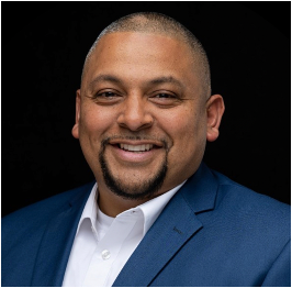 A man in a blue suit and white shirt is smiling for the camera.