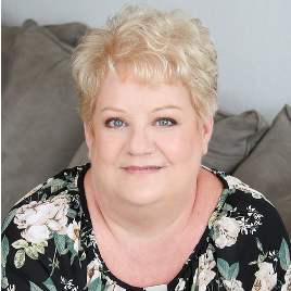 A woman is sitting on a couch wearing a floral shirt