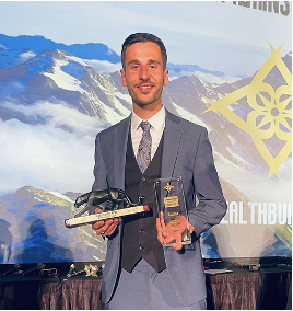 A man in a suit and tie is holding a trophy