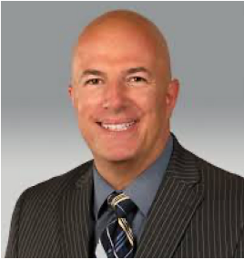 A bald man in a suit and tie is smiling for the camera.