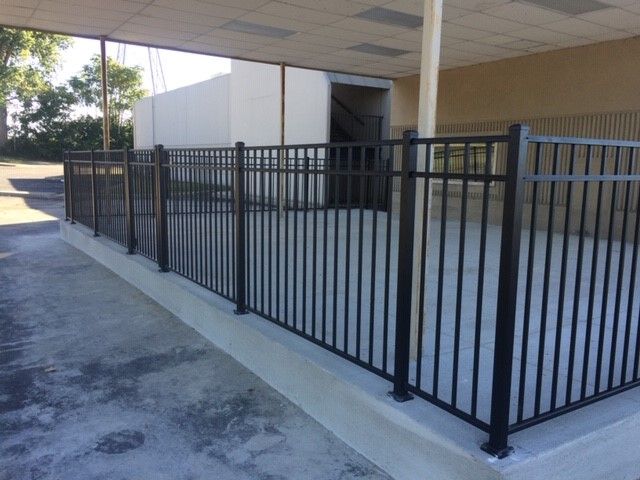 A black metal fence surrounds a concrete walkway