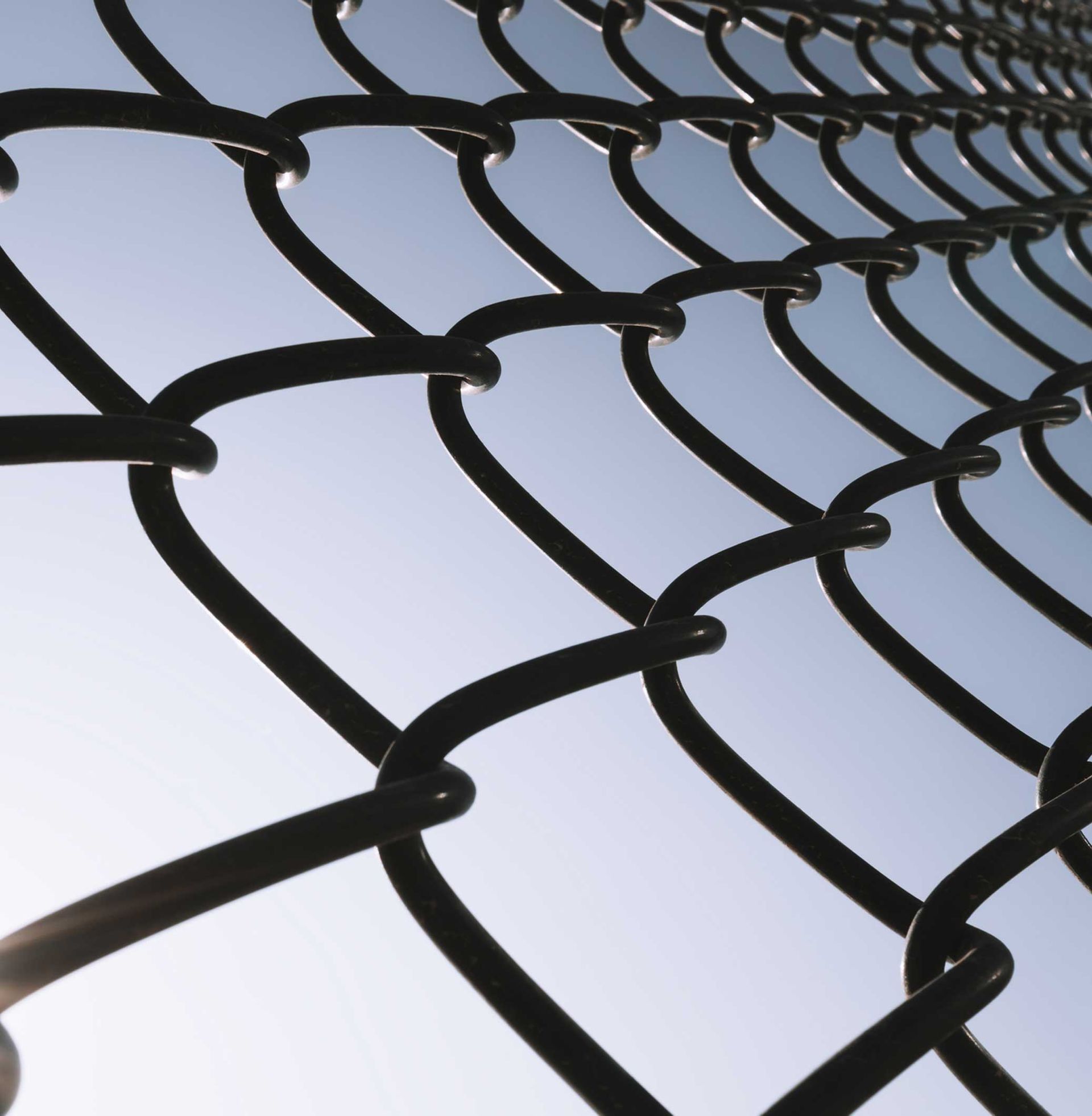 A chain link fence with a blue sky in the background.