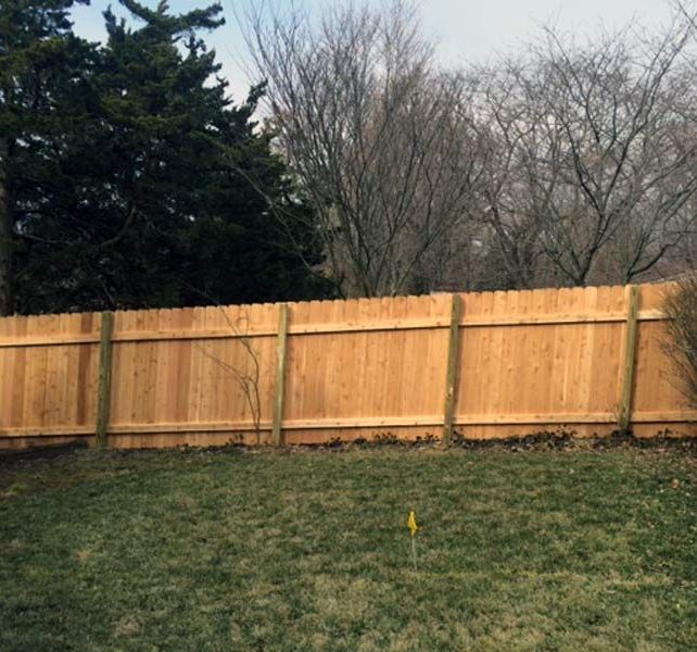 A close up of a wooden fence with a blue sky in the background.