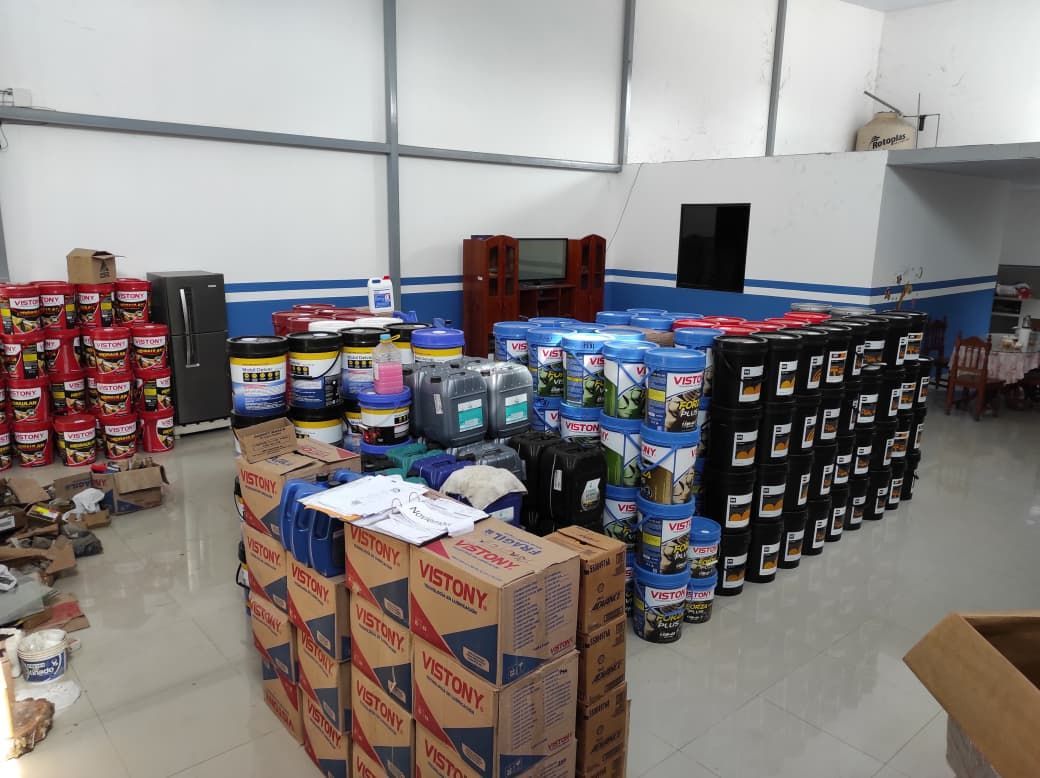 Dentro de un almacén, filas de cubos y cajas de aceite, estantes de productos
