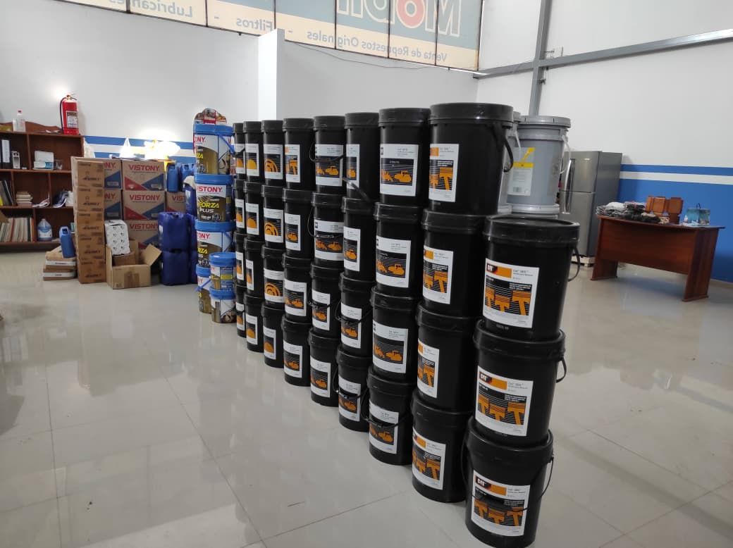 Filas de cubos negros con etiquetas apilados en una tienda. Cajas y productos adicionales al fondo.