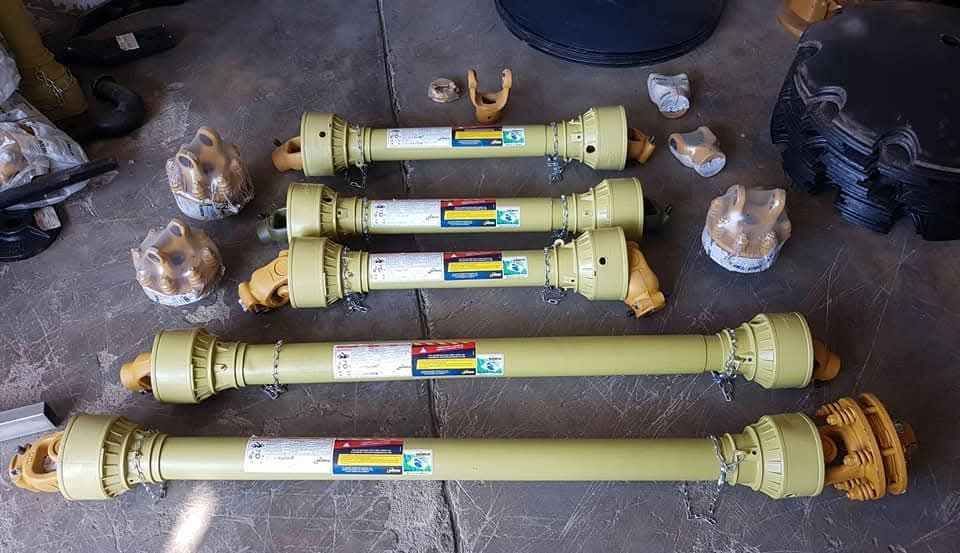 Cuatro ejes TDF agrícolas de color amarillo y piezas variadas sobre una superficie gris.