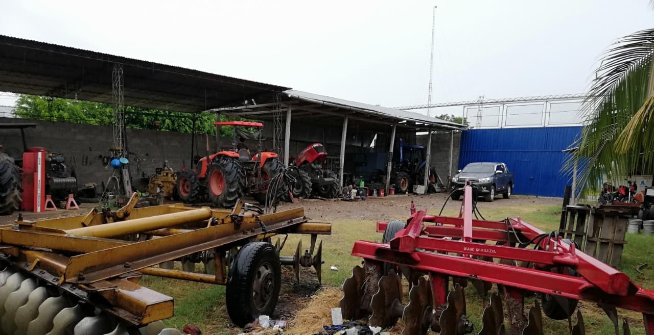 Equipos agrícolas, tractores y maquinaria estacionados bajo un área cubierta