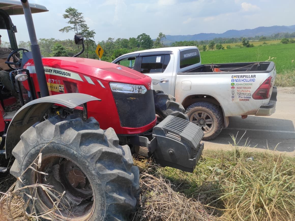 Tractor rojo y camión blanco estacionados al costado de una carretera en un entorno rural.