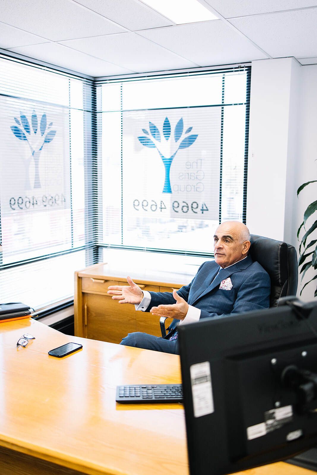 A Man In A Suit Is Sitting At A Desk In Front Of A Computer — The Garis Group  In Hamilton, NSW