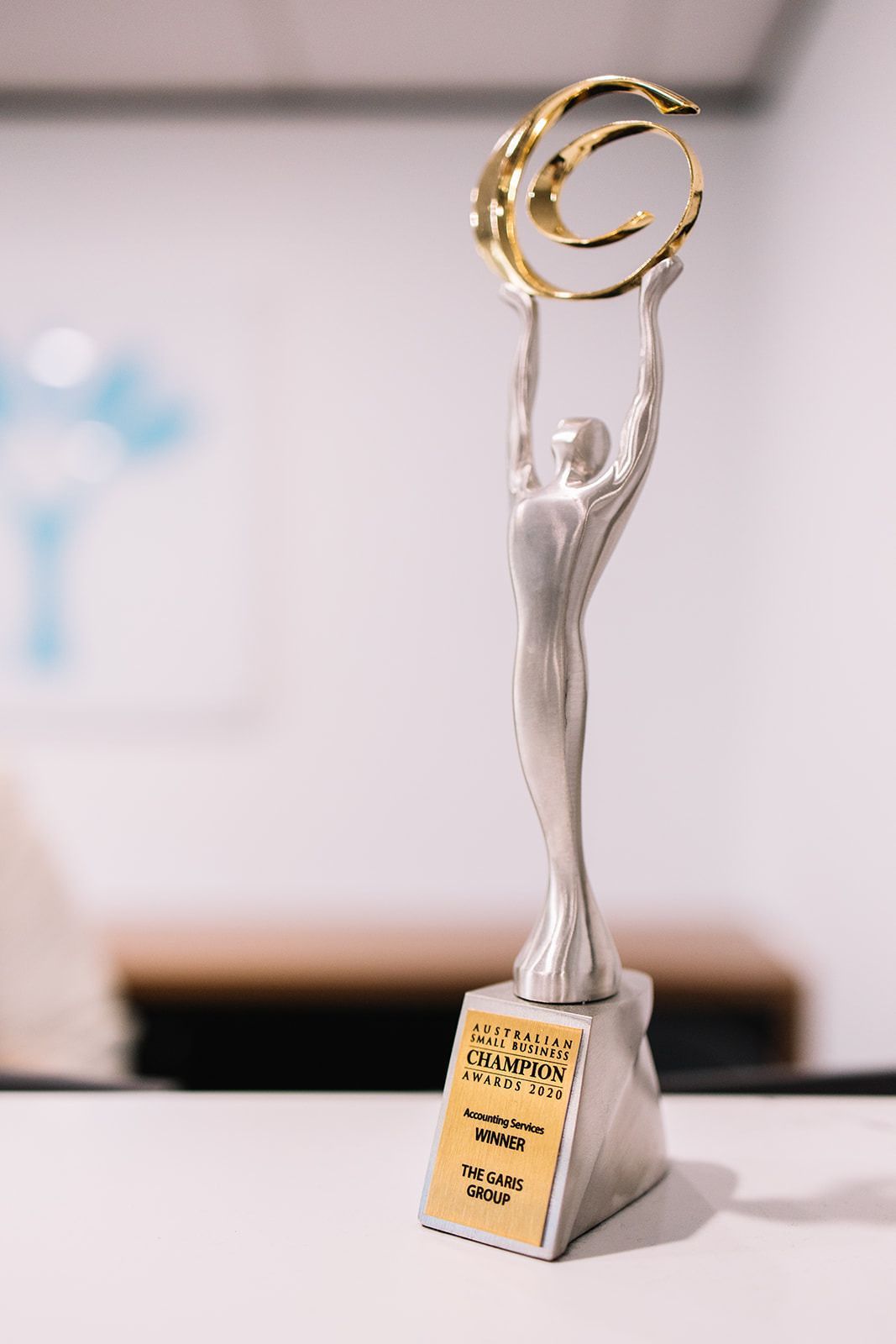 A Silver Statue Of A Woman Holding A Gold Ring Is Sitting On A Table — The Garis Group In Hamilton, NSW