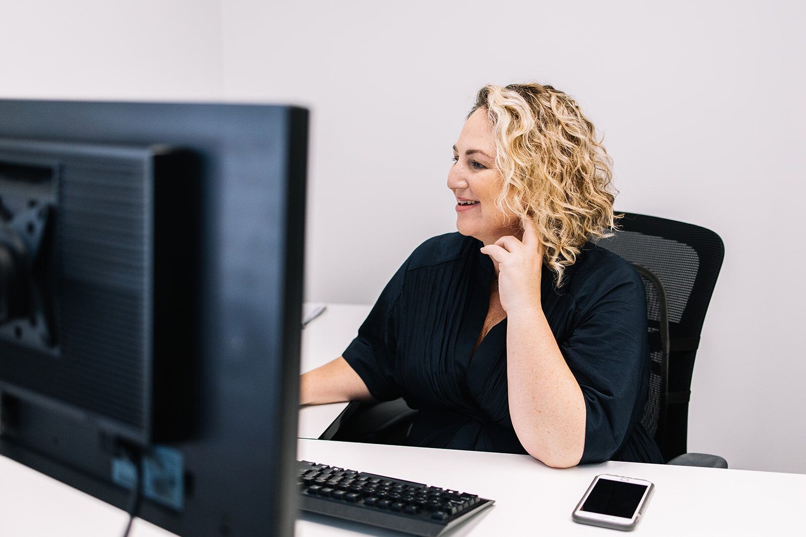 A Woman Is Sitting At A Desk In Front Of A Computer — The Garis Group  In Hamilton, NSW
