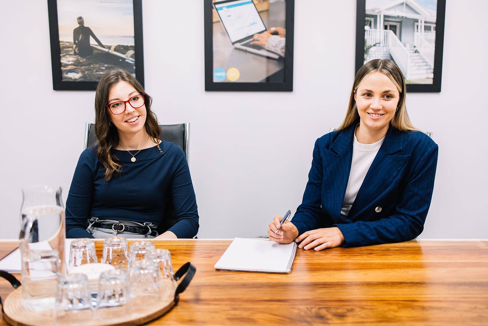 Two Women Are Sitting At A Wooden Table — The Garis Group  In Newcastle, NSW
