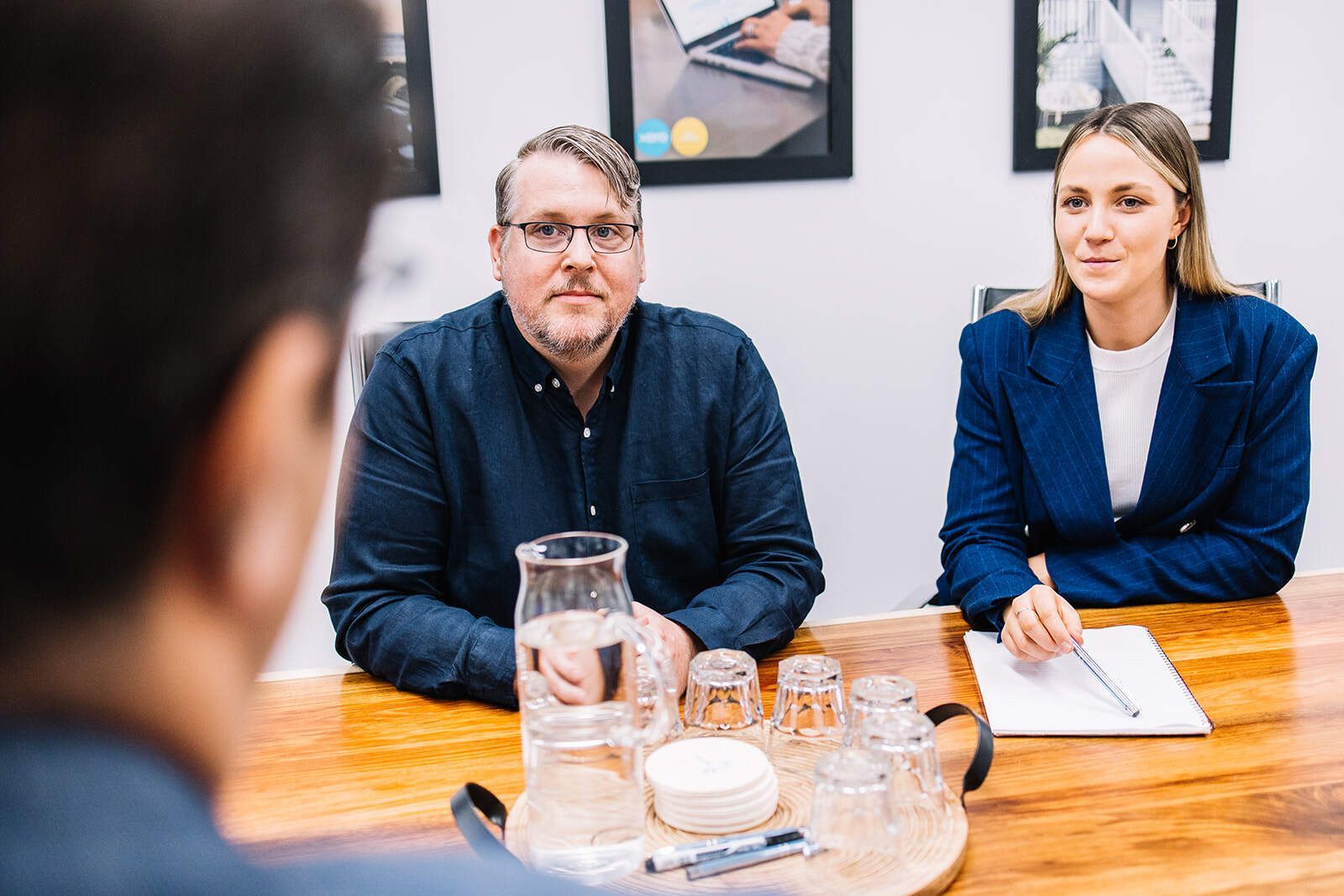 A Man And A Woman Are Sitting At A Table Having A Meeting — The Garis Group In Hamilton, NSW