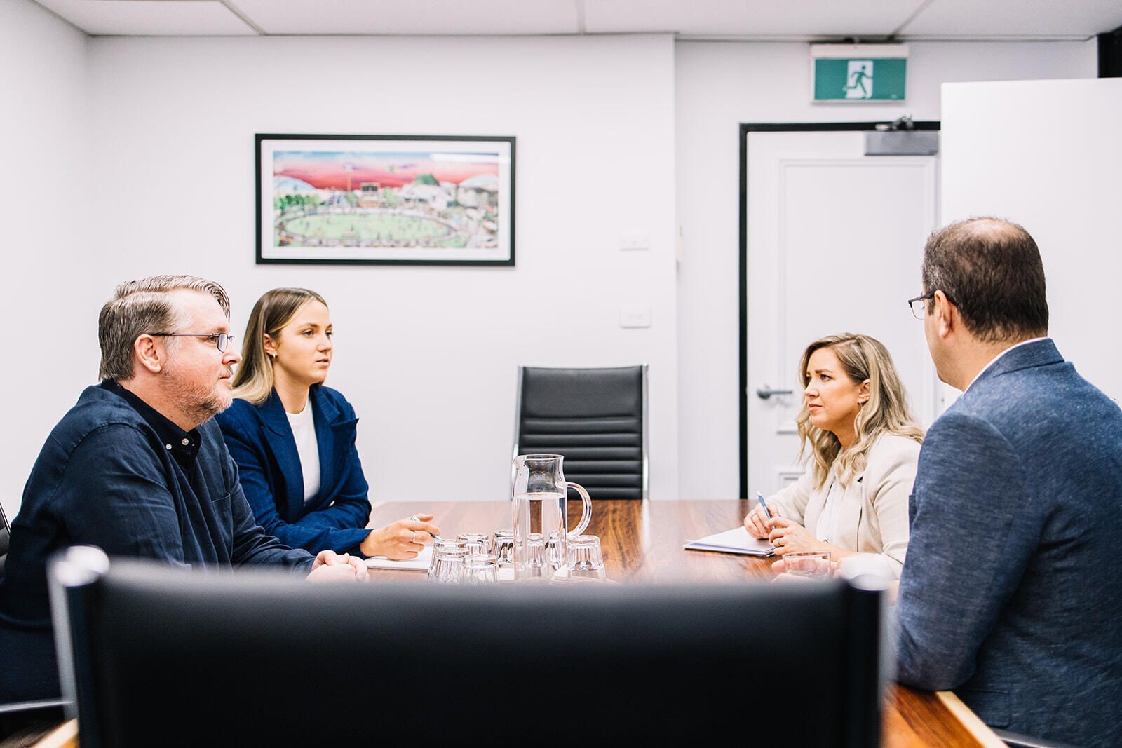 A Group Of People Are Sitting Around A Table In A Conference Room — The Garis Group In Sydney, NSW