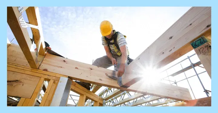 A Man Wearing A Hard Hat Is Working On A Wooden Structure — The Garis Group  In Hamilton, NSW 