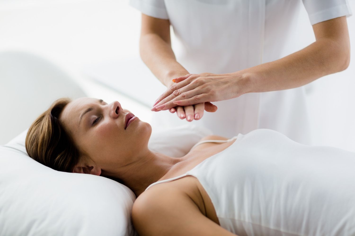 Woman receiving reiki treatment; hands hovering over her chest.