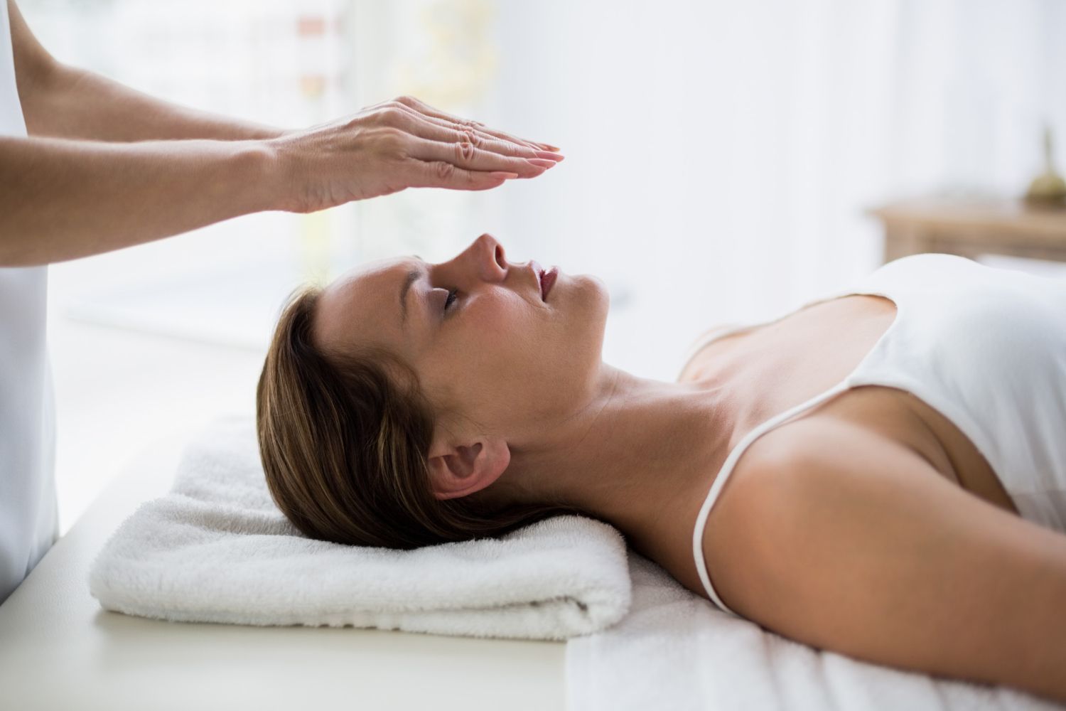 A woman is laying on a bed getting a healing treatment.