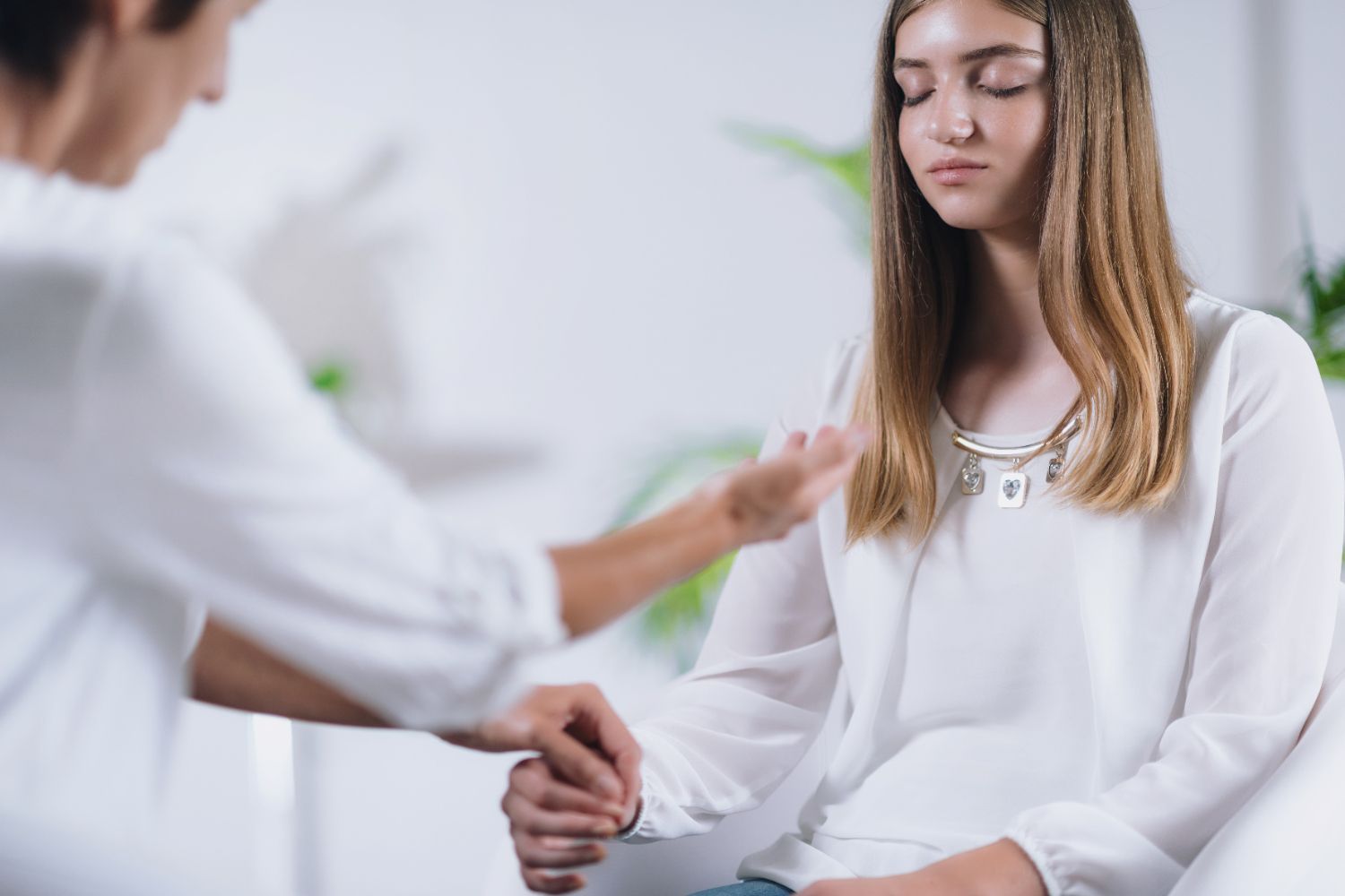 A woman is sitting in a chair while a man holds her hand.