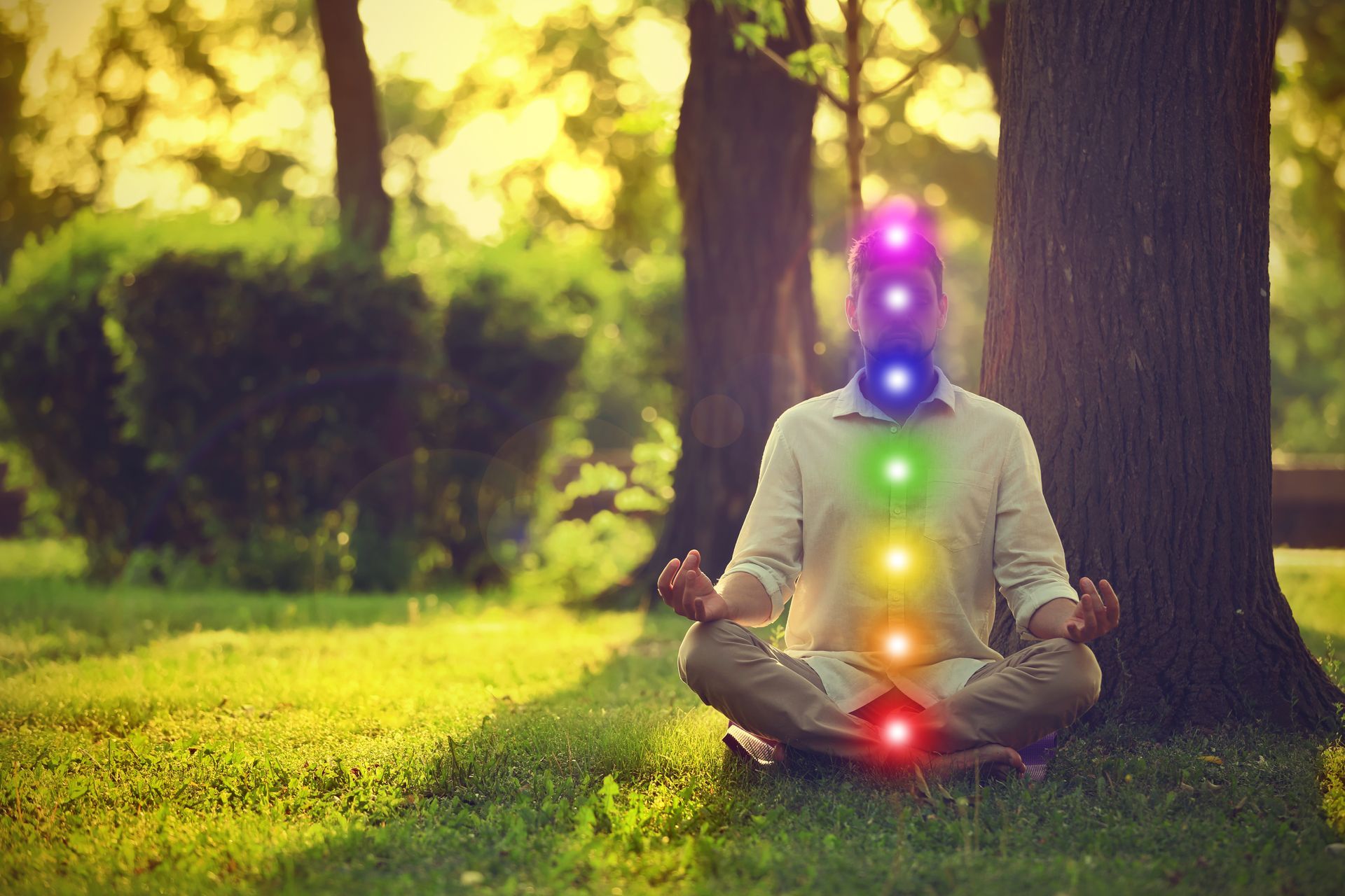 Person meditating outdoors with chakra colors overlaid.