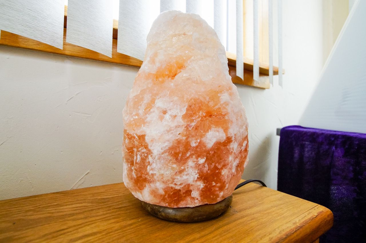 A salt lamp is sitting on a wooden table next to a window.