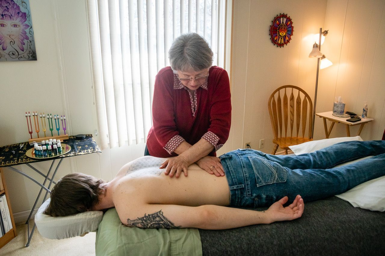 A woman is giving a man a massage on a bed.