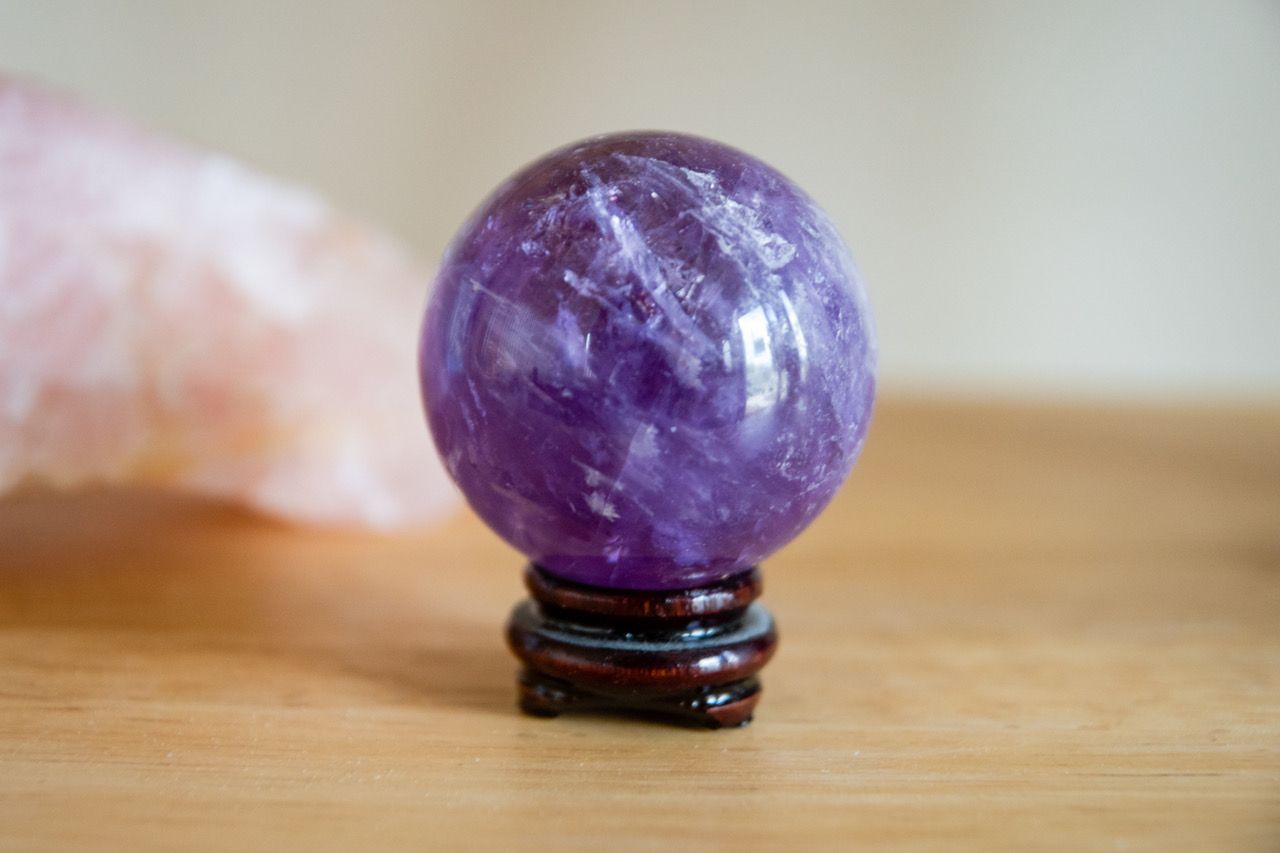 A purple crystal ball is sitting on a wooden table.