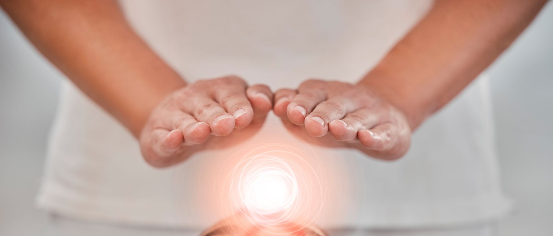 Person's hands cupped around a glowing orb, against a white background.