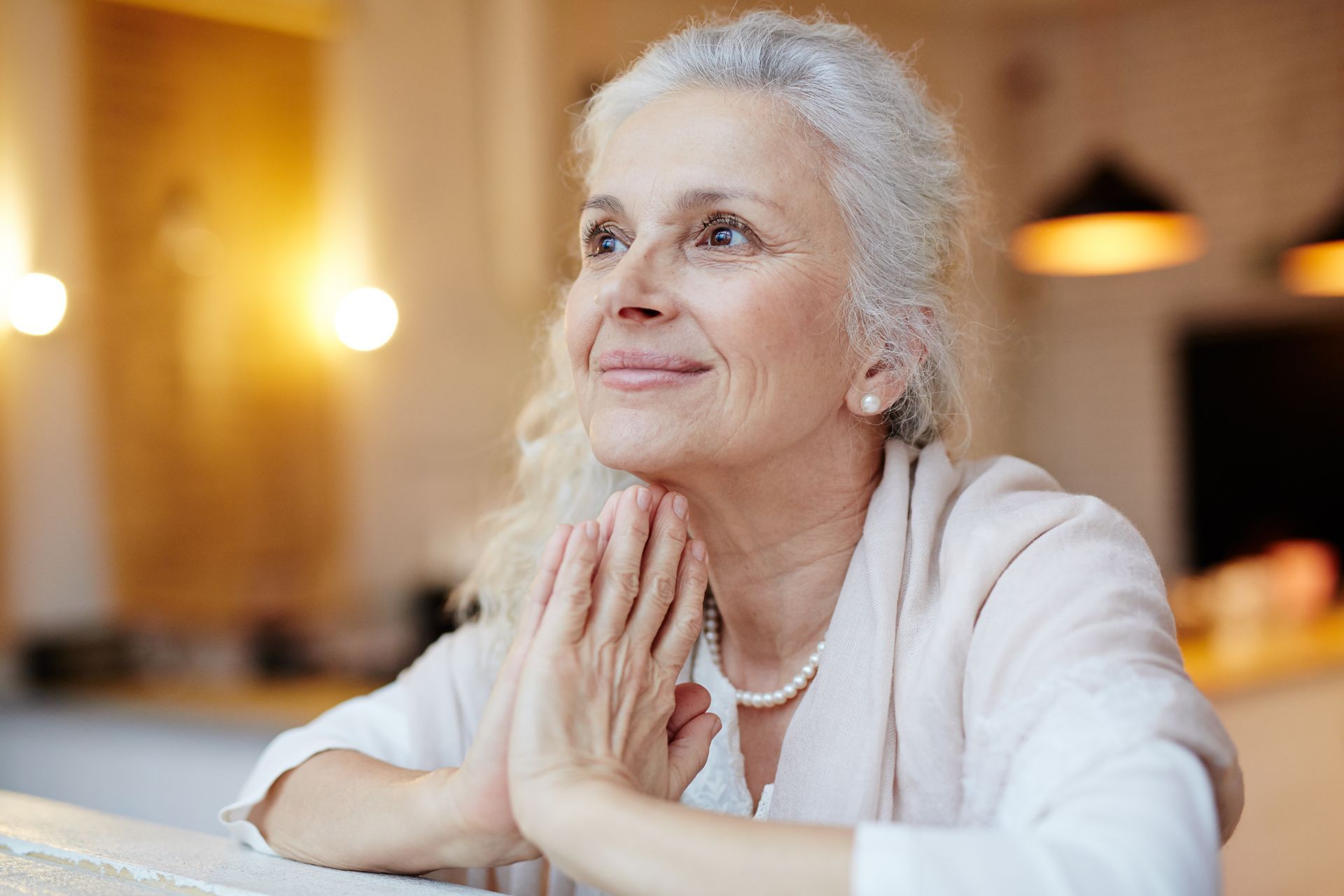 older woman praying hands with smile
