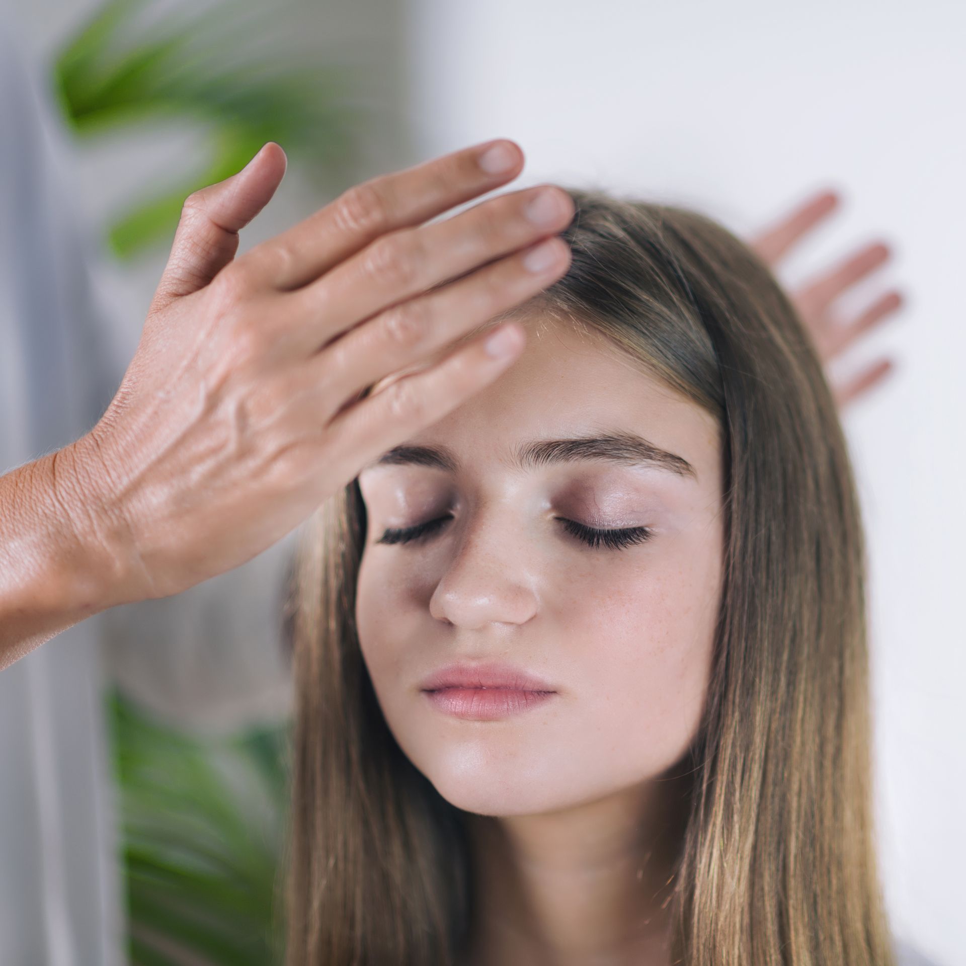 A woman with her eyes closed is getting a massage from a man.