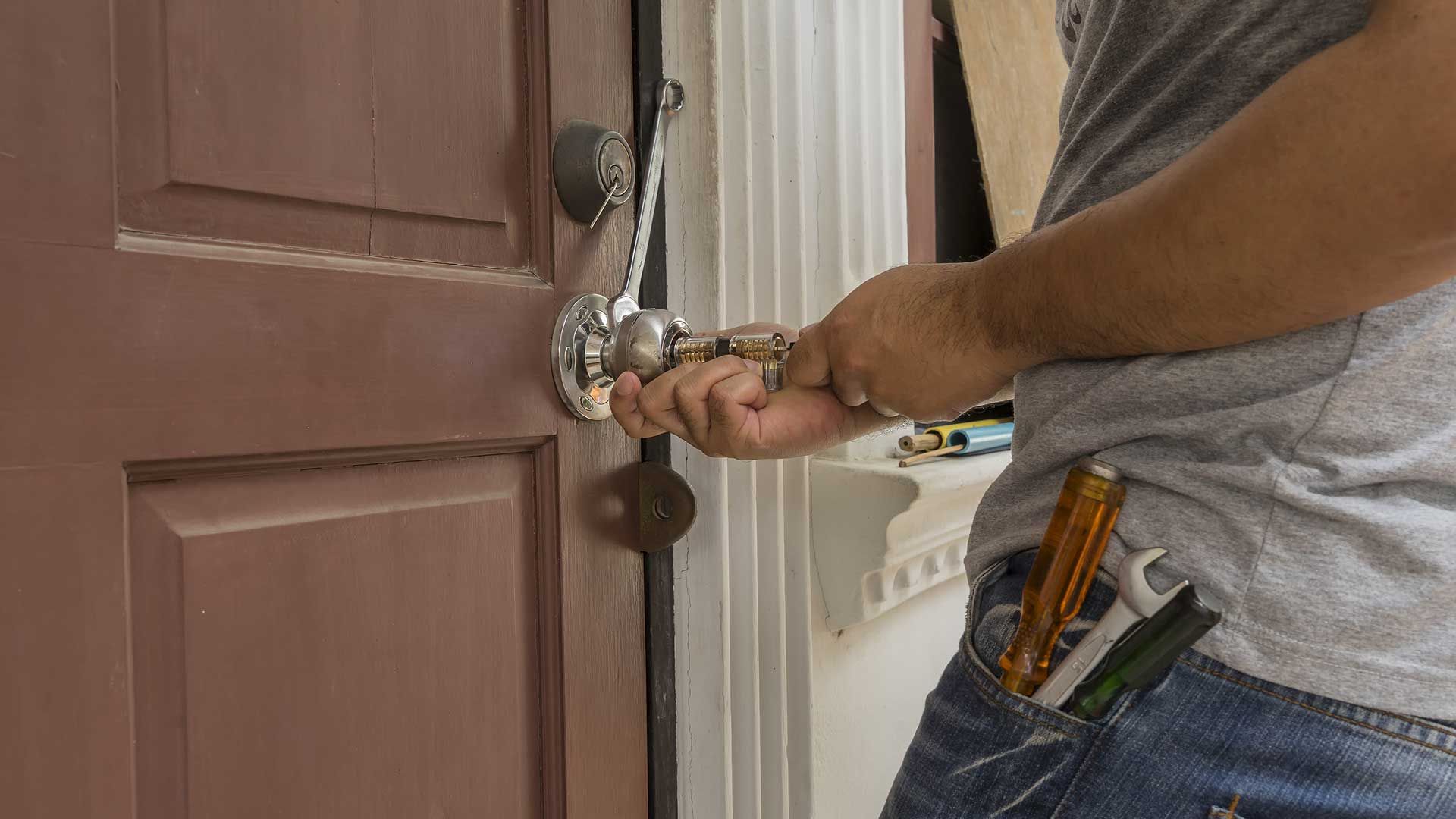 A man is fixing a door handle with a screwdriver.