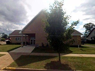 A large wooden building with a parking lot in front of it.