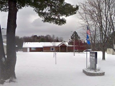 A snowy yard with a house in the background