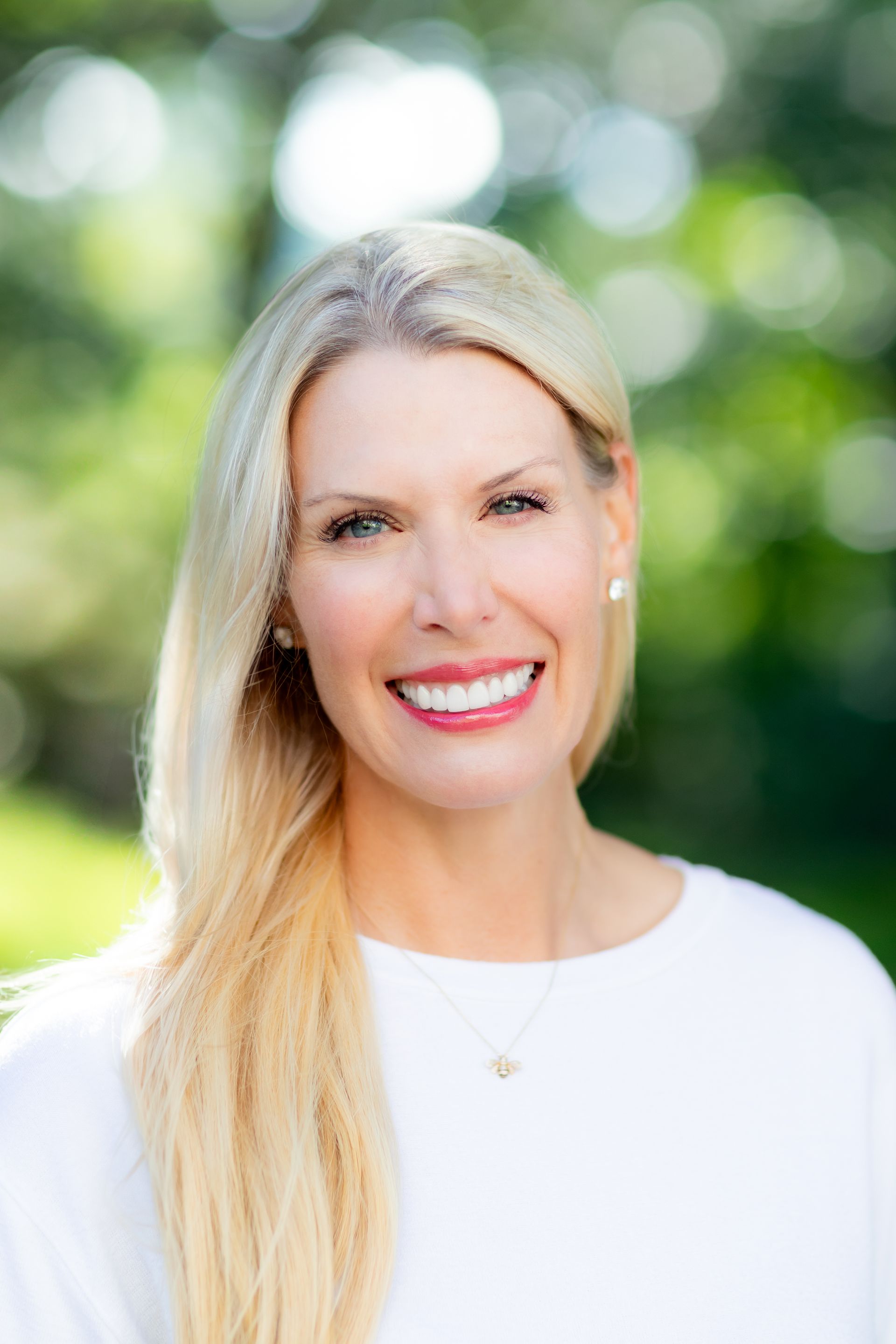 A woman in a white dress is smiling for the camera.
