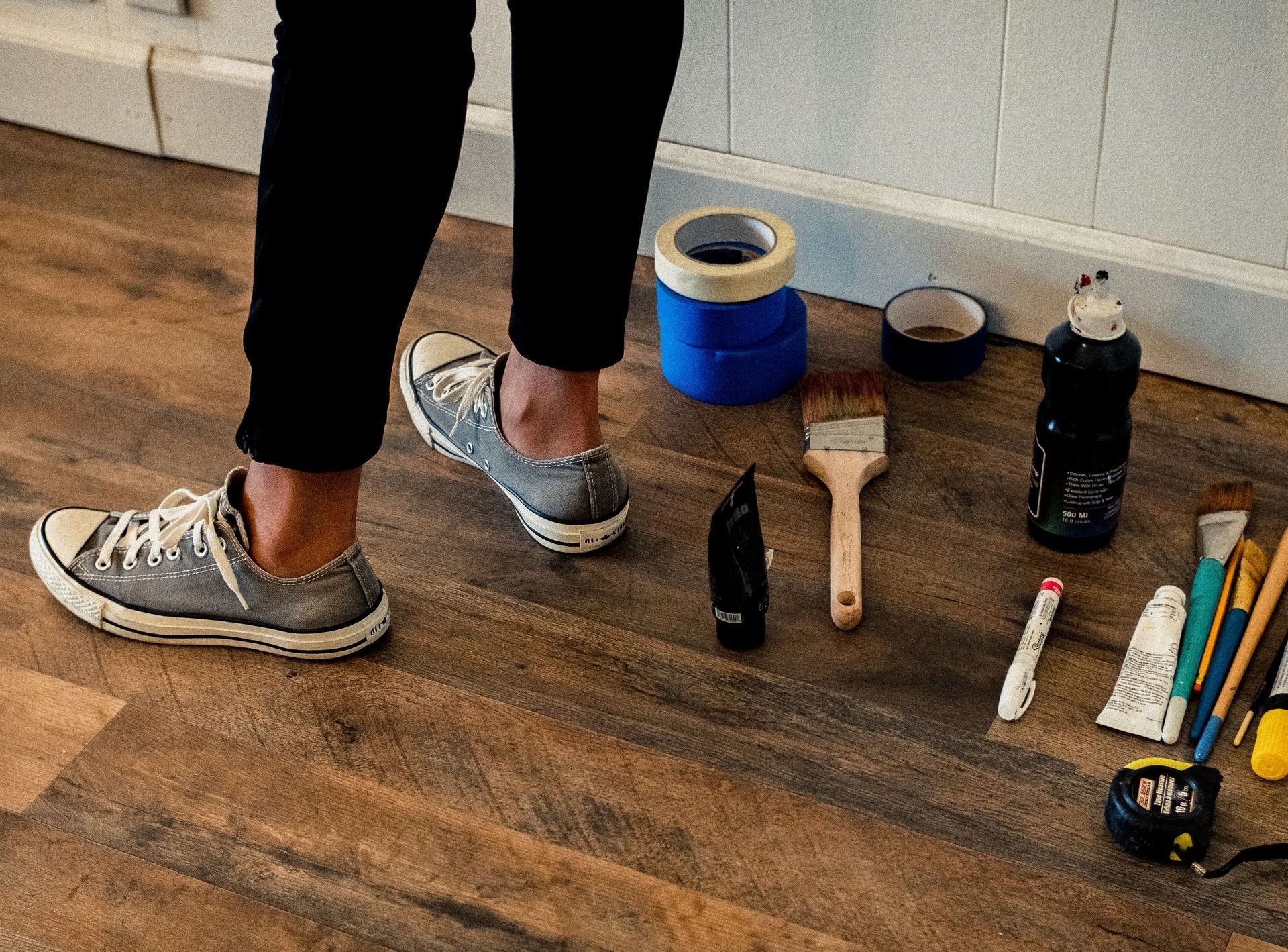 a person wearing converse shoes is standing on a wooden floor surrounded by tools