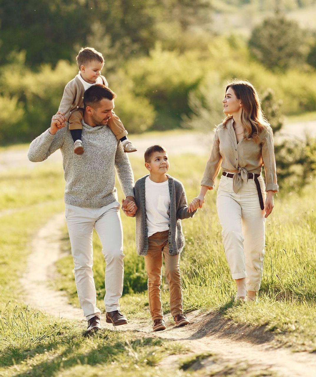 a family is walking down a dirt road holding hands