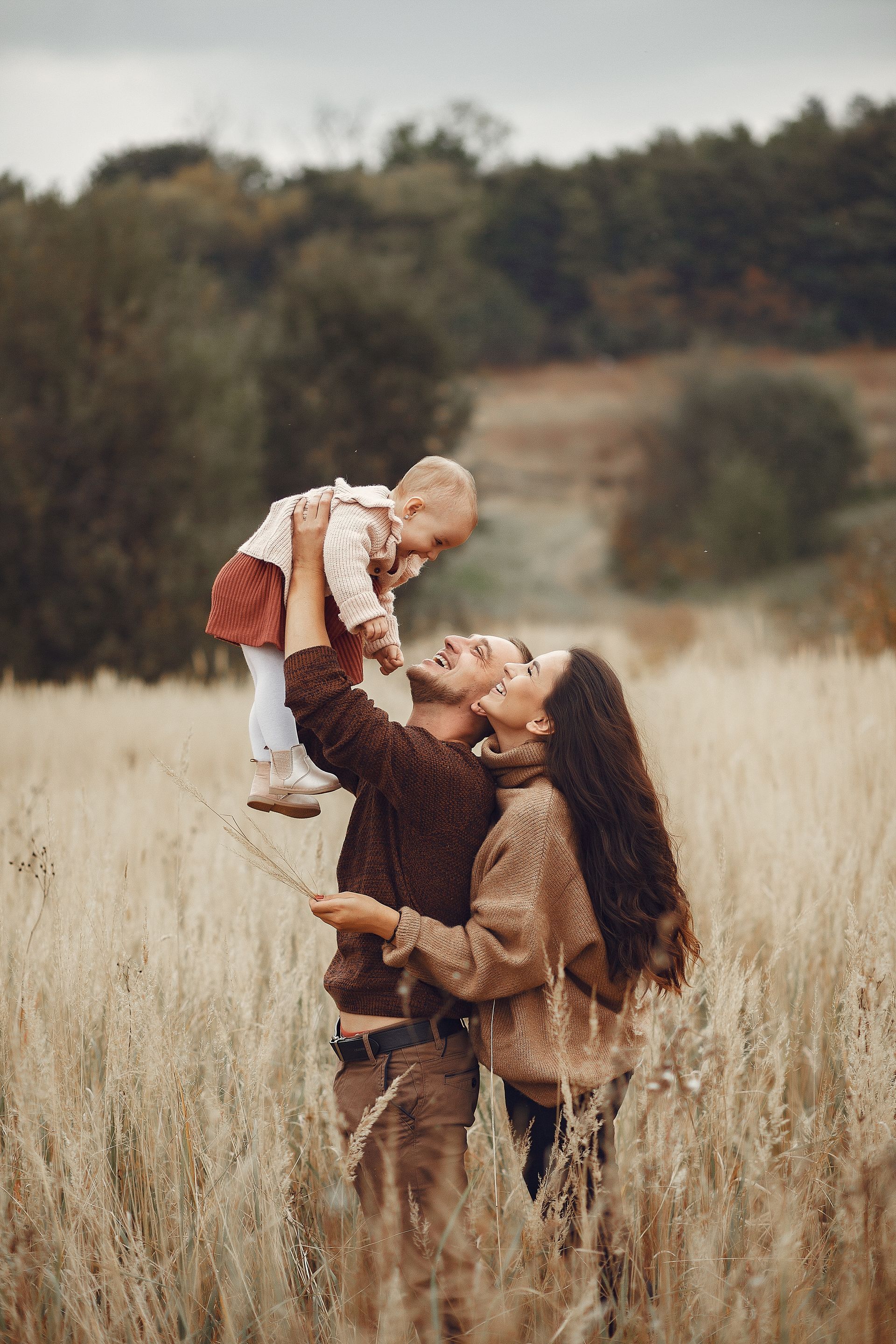 a man and woman holding a baby in a field