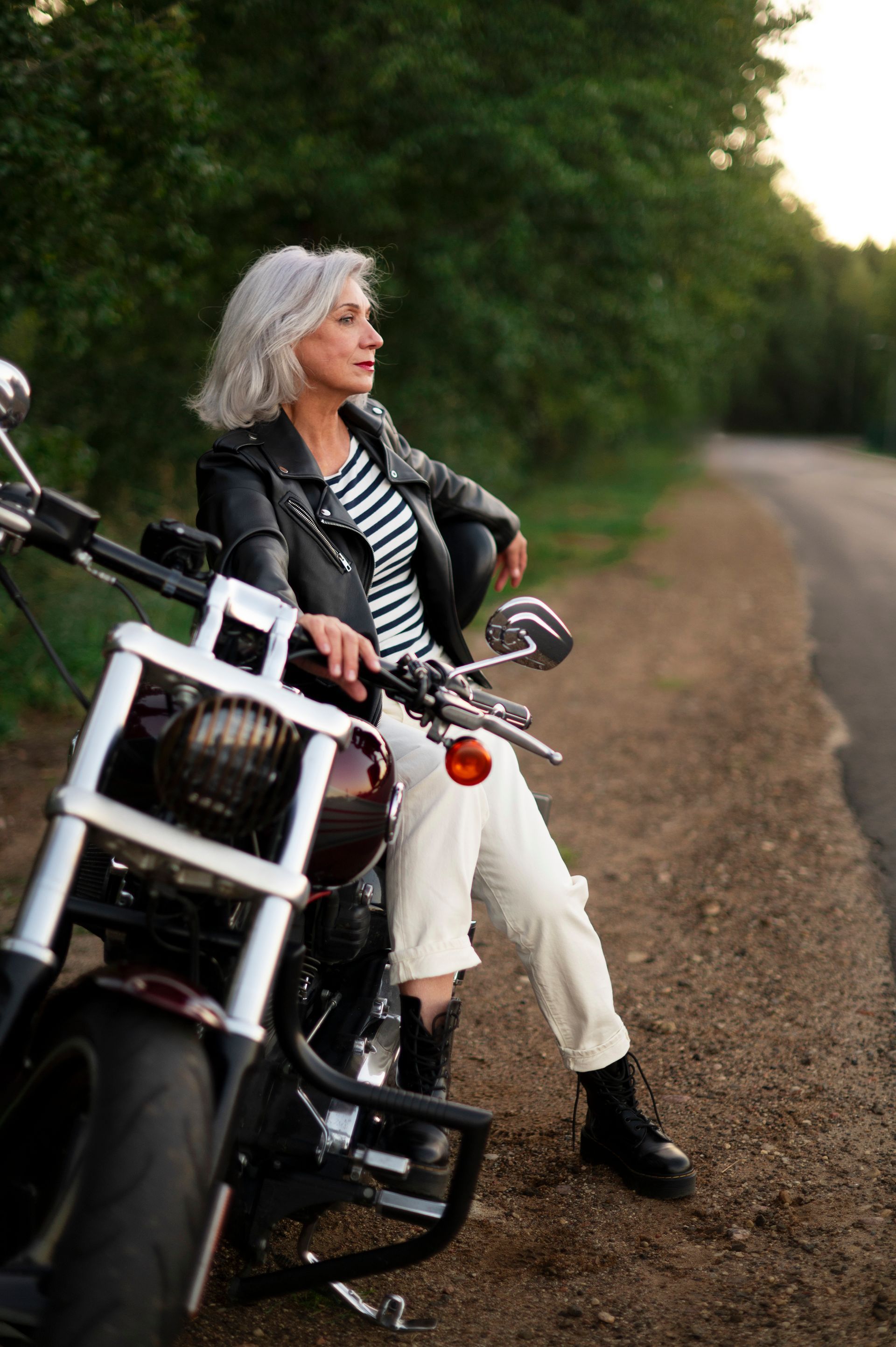 a woman sits on a motorcycle on the side of the road
