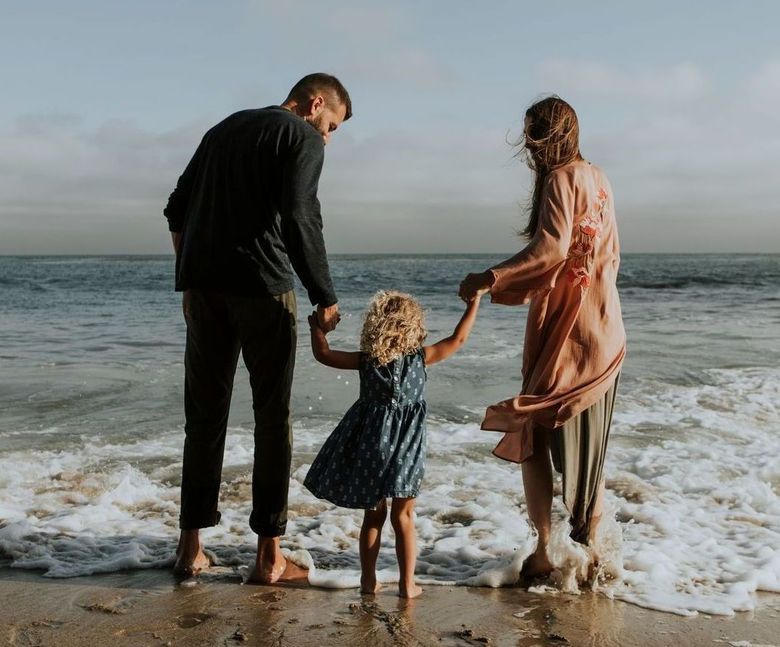 a family standing on the beach holding hands