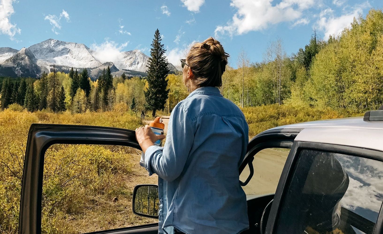a woman looks out the window of her car at a mountain range