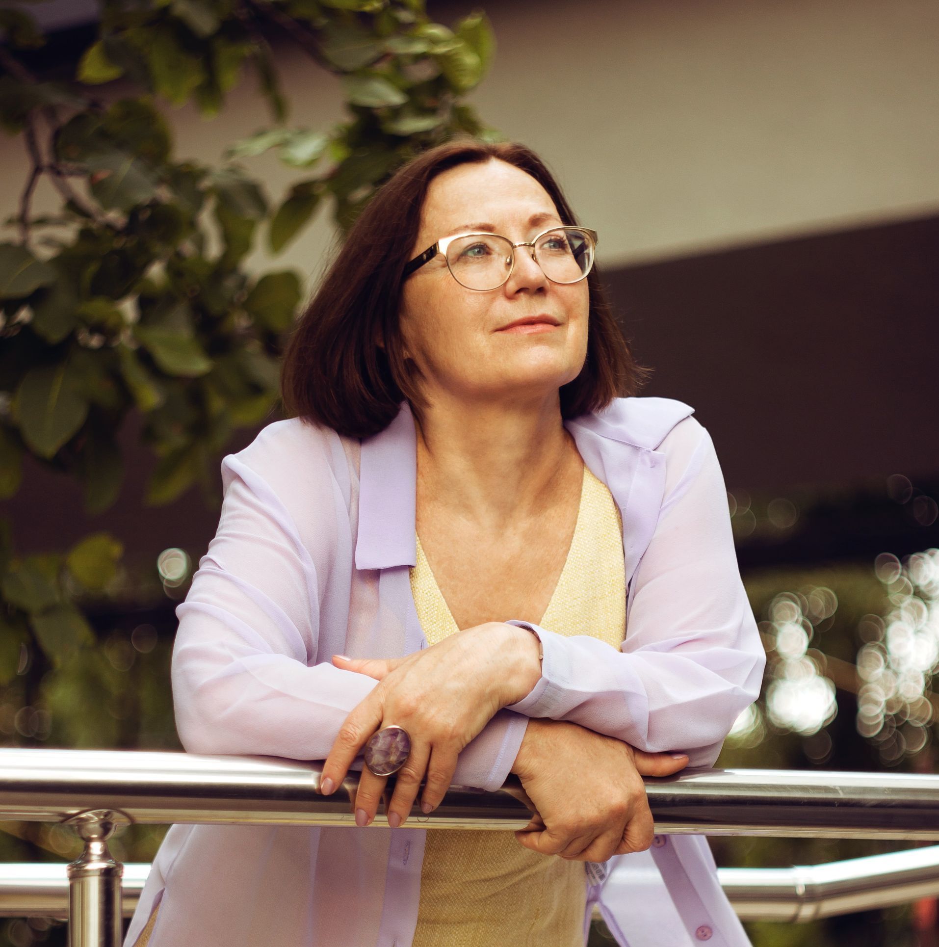 a professional woman wearing glasses leans on a railing