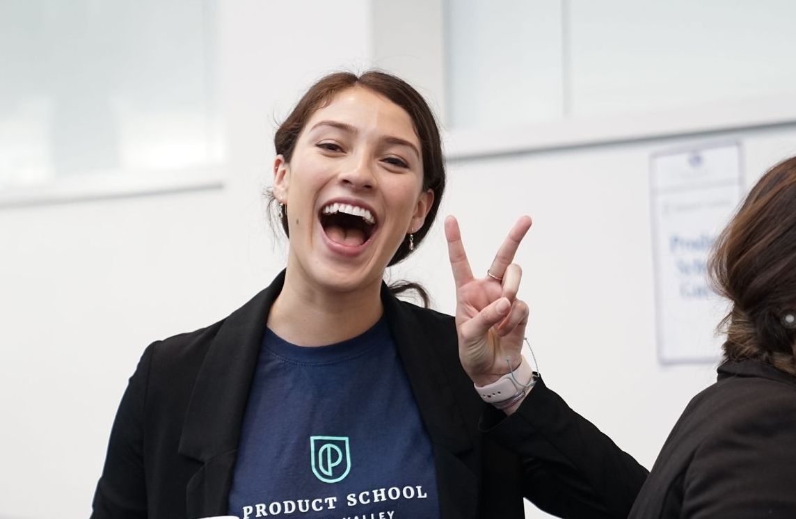 a woman wearing a product school shirt giving a peace sign
