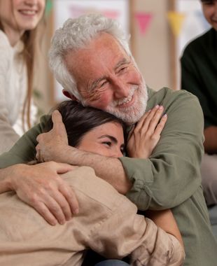 an older man is hugging a younger woman