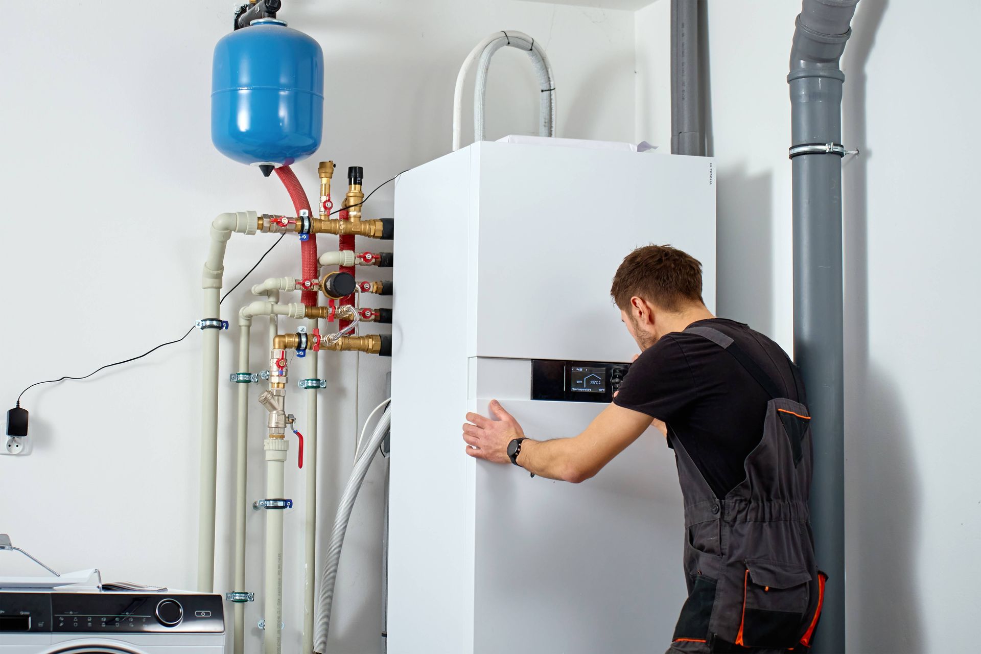HVAC technician inspecting and adjusting residential boiler controls during routine maintenance. HVAC technician inspecting and adjusting residential boiler controls during routine maintenance.