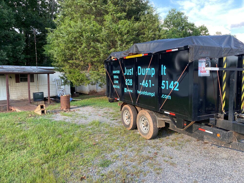 A dumpster on a trailer is parked in front of a house.